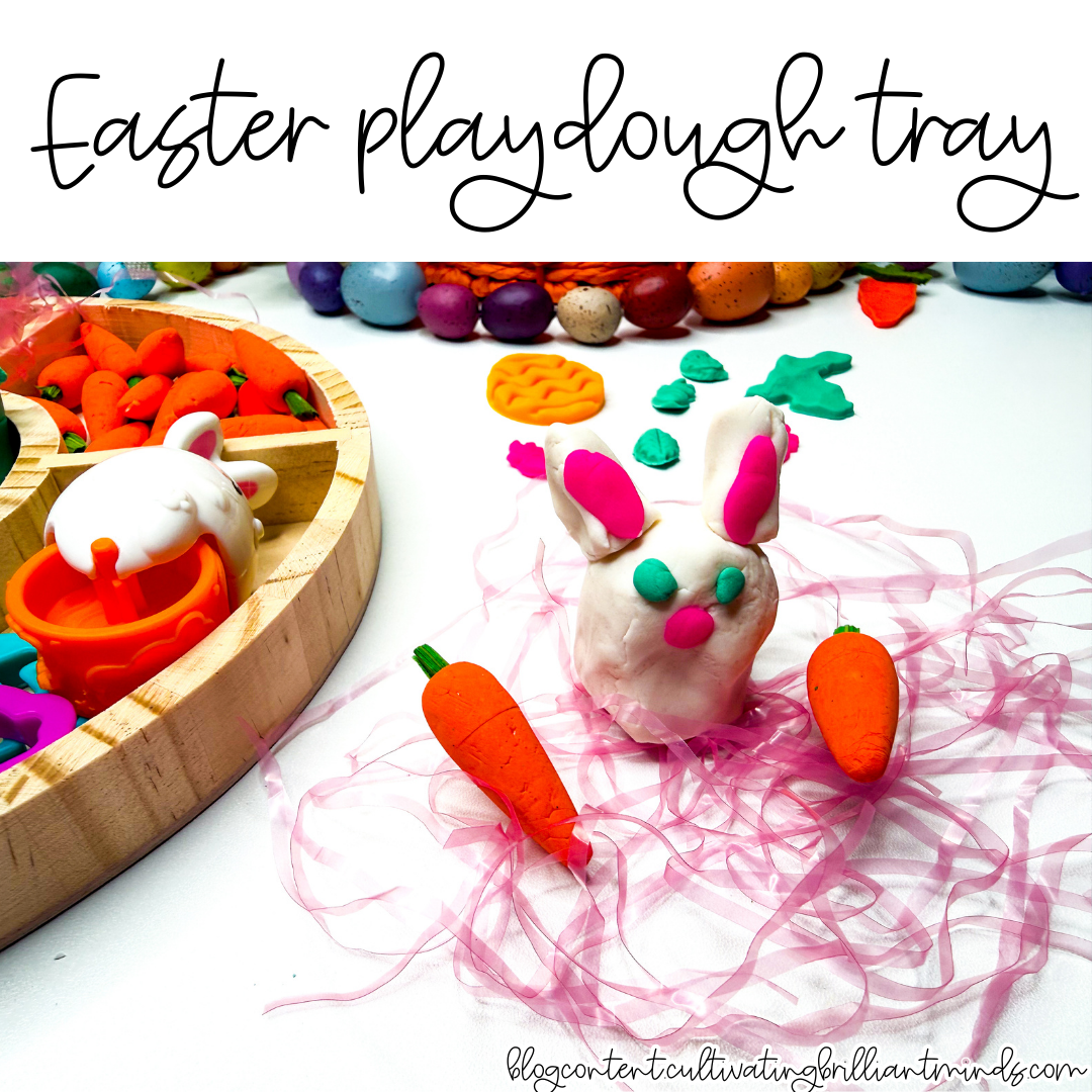 an easter playdough tray with mini carrots, pom poms, and easter grass